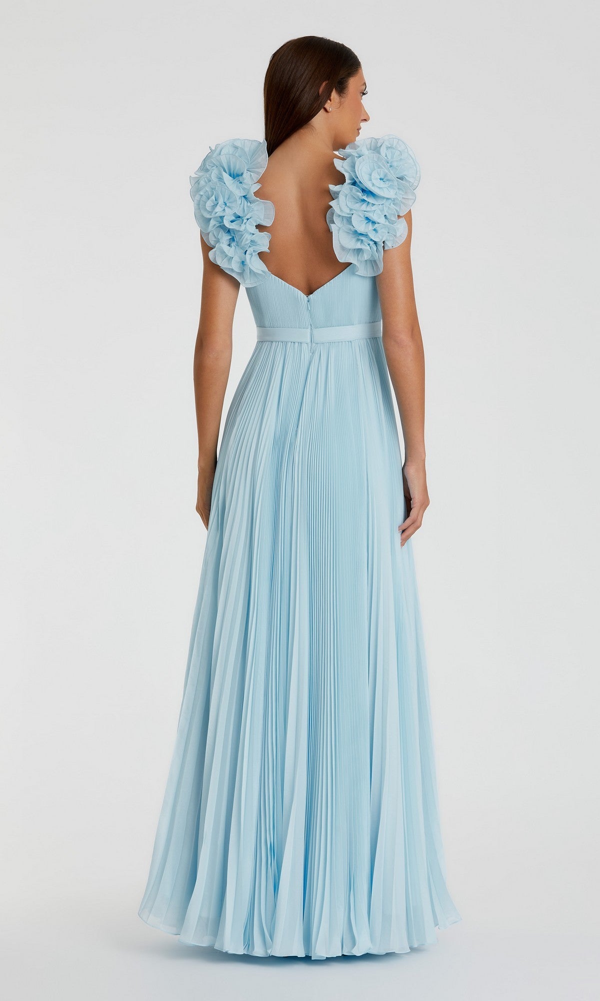 A woman is shown from the back wearing the Mac Duggal 49979, a long formal light blue pleated organza dress featuring large floral shoulder embellishments.